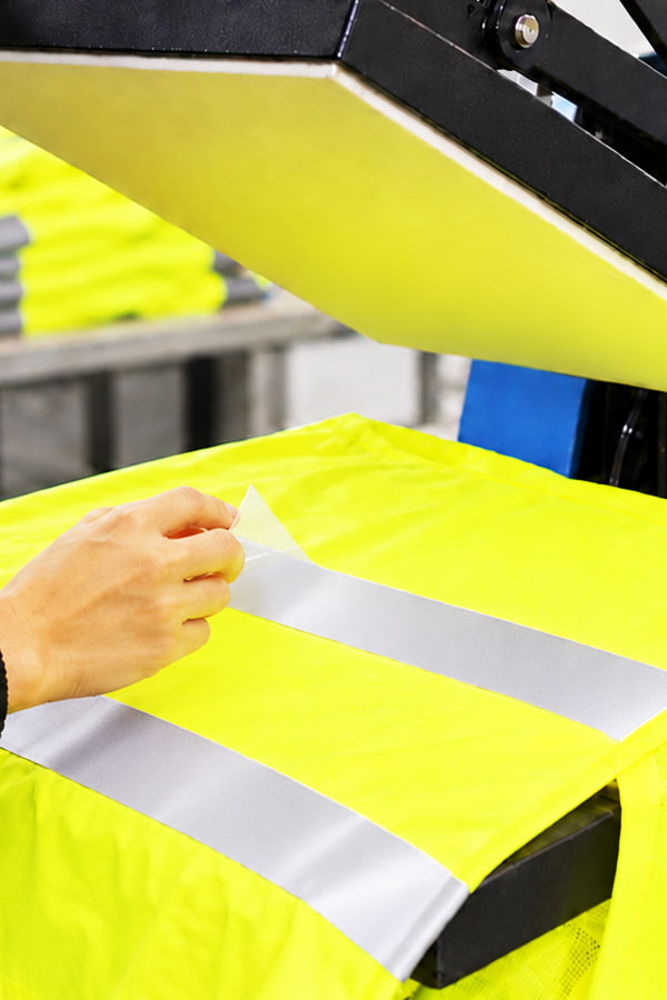 Nastro retroriflettente termoadesivo in applicazione su abbigliamento di sicurezza con pressa termica